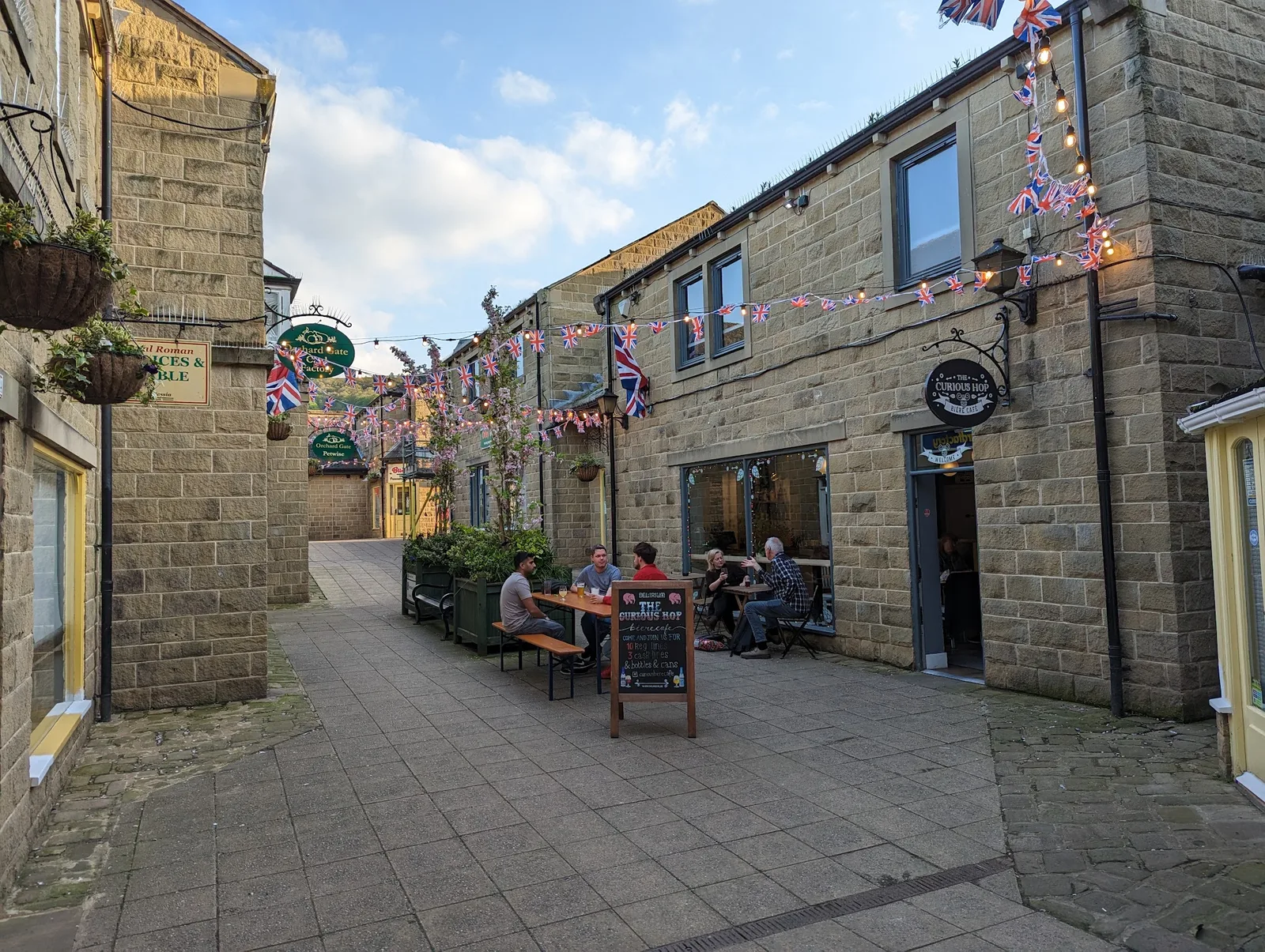 The Curious Hop courtyard on Orchard Gate, with stone buildings, bunting and outdoor tables