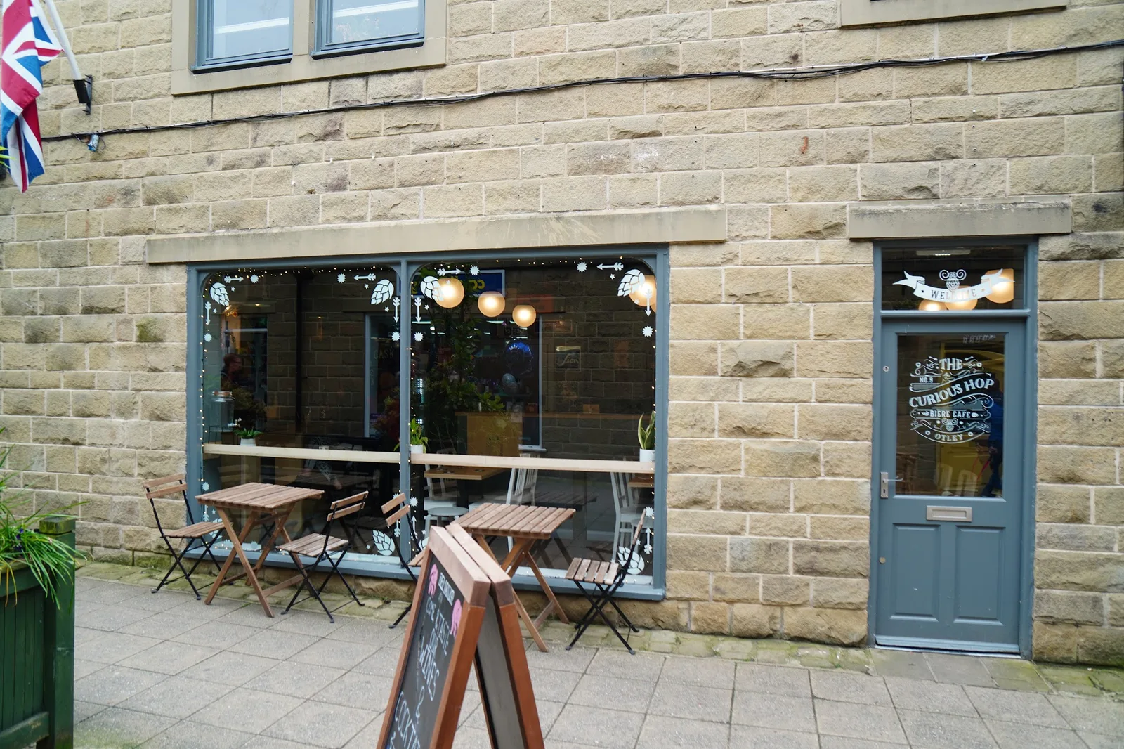 The Curious Hop entrance at 9 Orchard Gate, with white lettering on the door and tables outside
