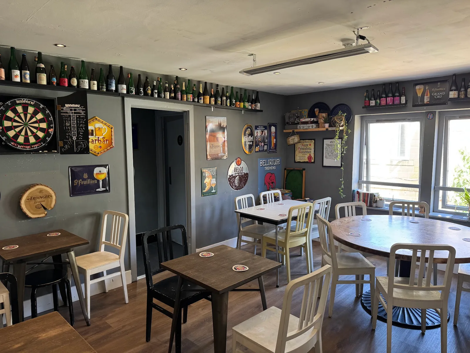 Tables and chairs inside The Curious Hop, surrounded by Belgian beer signs and bottles